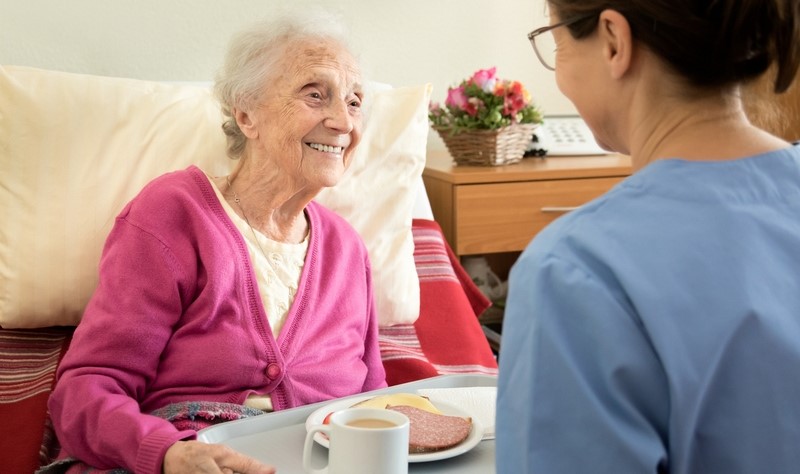 Home caregiver with senior adult woman, serving a meal Dobrovolníctvo