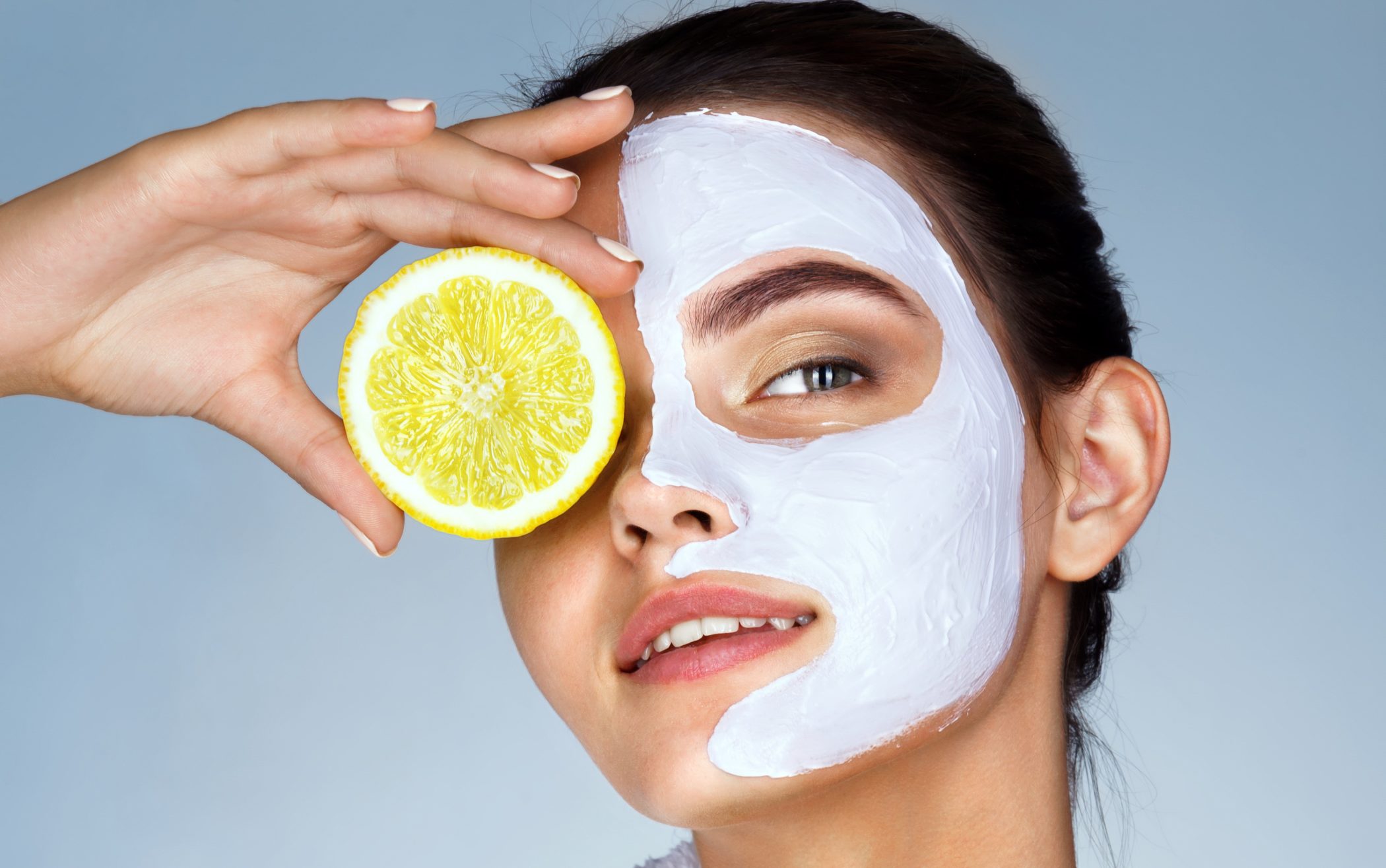 Funny beautiful model holding lemon slices up to her eyes.
